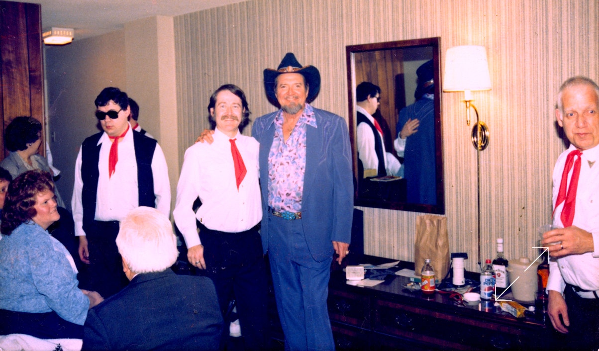 Hank Thompson and Ryan Thomson pose for a picture in the dressing room before a concert, along with other band mates and fans.